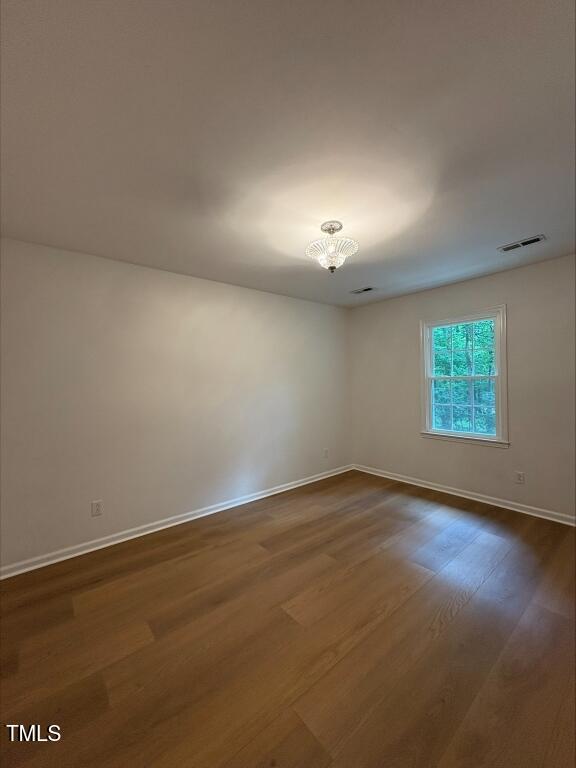 1300 Seabrook Ave, Cary, NC 27511 - empty room with dark wood finished floors and a chandelier
