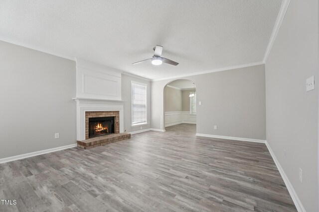 105 Leacroft Way, Durham, NC 27703 - unfurnished living room with a textured ceiling, a ceiling fan, a brick fireplace, wood finished floors, and crown molding