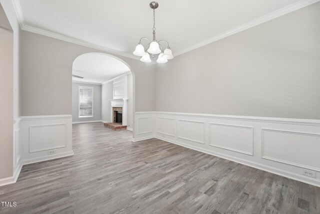 105 Leacroft Way, Durham, NC 27703 - unfurnished dining area with arched walkways, ornamental molding, wood finished floors, a decorative wall, and a chandelier