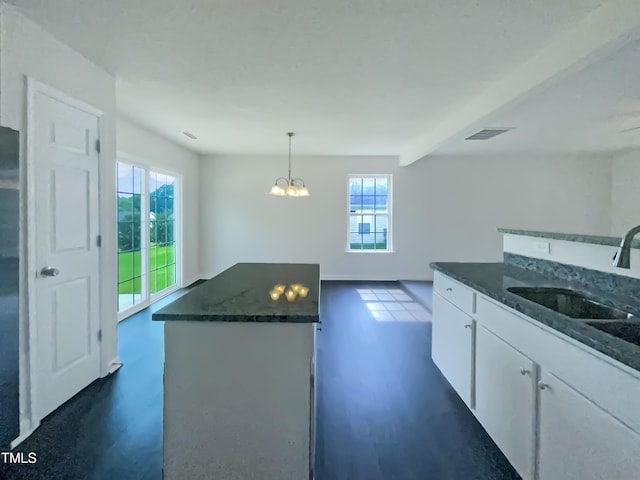 308 Quartz Dr, Durham, NC 27703 - kitchen with dark wood-style flooring, white cabinetry, dark stone counters, a center island, and beamed ceiling