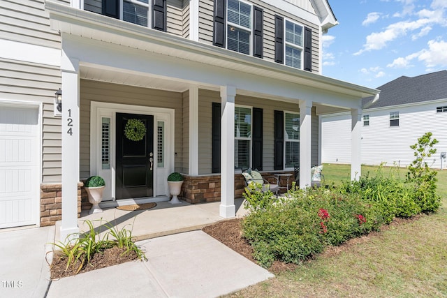 124 Airlie Place Ln, Willow Springs, NC 27592 - view of exterior entry with a porch, a garage, and stone siding