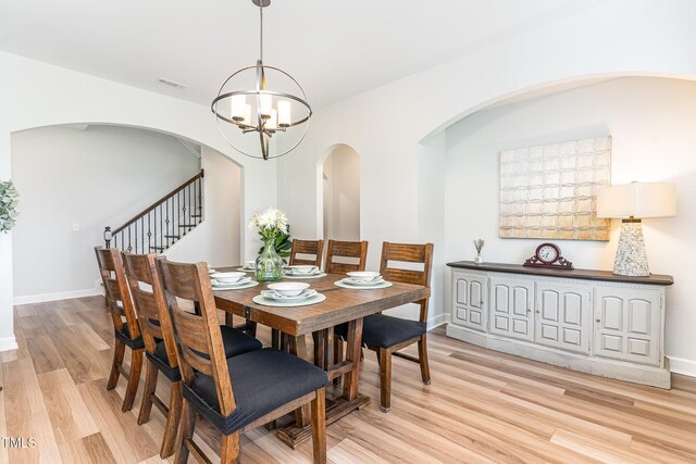 124 Airlie Place Ln, Willow Springs, NC 27592 - dining space featuring a chandelier, light wood-style flooring, arched walkways, and stairs