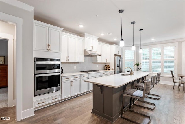 10310 Sablewood Dr Unit 115, Raleigh, NC 27617 - kitchen with appliances with stainless steel finishes, a kitchen island with sink, light countertops, light wood-style floors, and recessed lighting