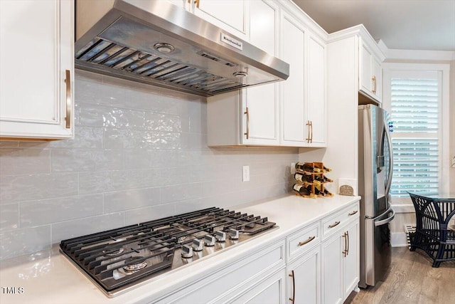 10310 Sablewood Dr Unit 115, Raleigh, NC 27617 - kitchen with island exhaust hood, stainless steel appliances, light countertops, white cabinetry, and decorative backsplash