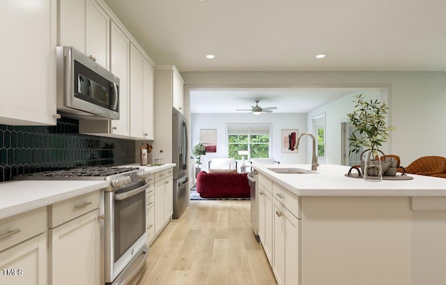 1216 Hardin Hill Ln, Knightdale, NC 27545 - kitchen with appliances with stainless steel finishes, light wood finished floors, a ceiling fan, decorative backsplash, and light countertops