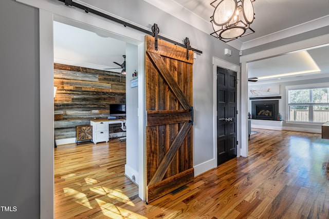405 Culvert St, Apex, NC 27502 - hallway featuring a barn door, wooden walls, wood finished floors, and an accent wall
