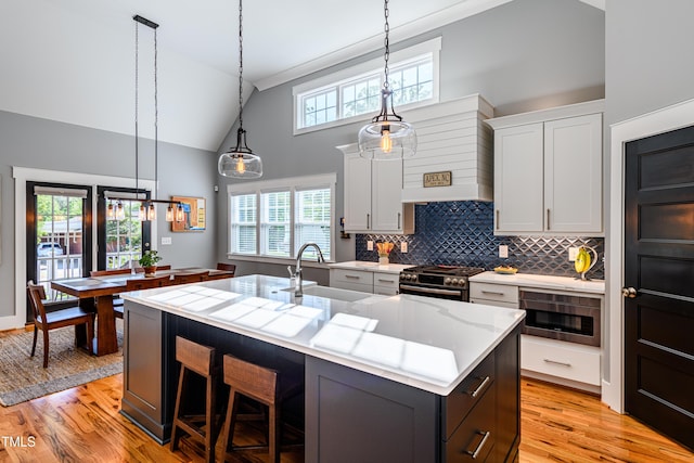 405 Culvert St, Apex, NC 27502 - kitchen with stainless steel range with gas cooktop, custom exhaust hood, a kitchen island with sink, tasteful backsplash, and white cabinetry