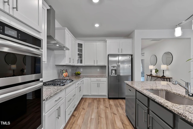265 Purple Aster St, Youngsville, NC 27596 - kitchen with appliances with stainless steel finishes, wall chimney exhaust hood, white cabinetry, light wood-type flooring, and recessed lighting