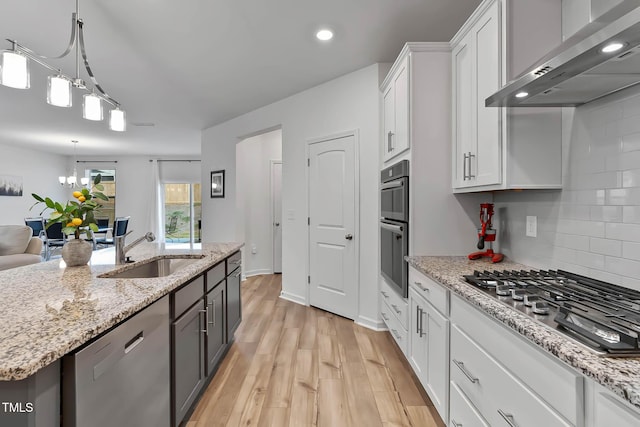 265 Purple Aster St, Youngsville, NC 27596 - kitchen featuring range hood, stainless steel appliances, white cabinetry, light wood-style floors, and tasteful backsplash