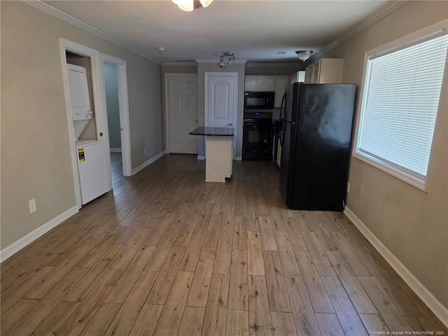 4969 Arlington St, Hope Mills, NC 28348 - kitchen featuring black appliances, stacked washing machine and dryer, light wood-style floors, white cabinets, and crown molding