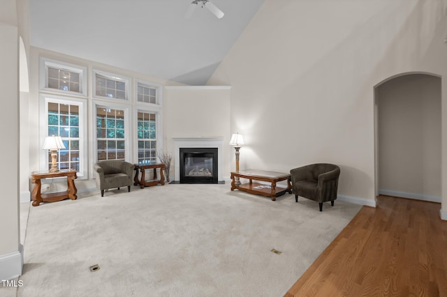 1040 Bellenden Dr, Durham, NC 27713 - carpeted living room with high vaulted ceiling, arched walkways, a fireplace with flush hearth, and a ceiling fan