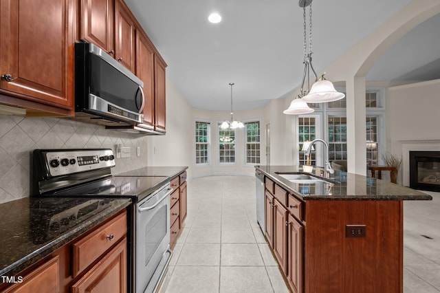 1040 Bellenden Dr, Durham, NC 27713 - kitchen featuring appliances with stainless steel finishes, backsplash, dark stone counters, arched walkways, and light tile patterned flooring