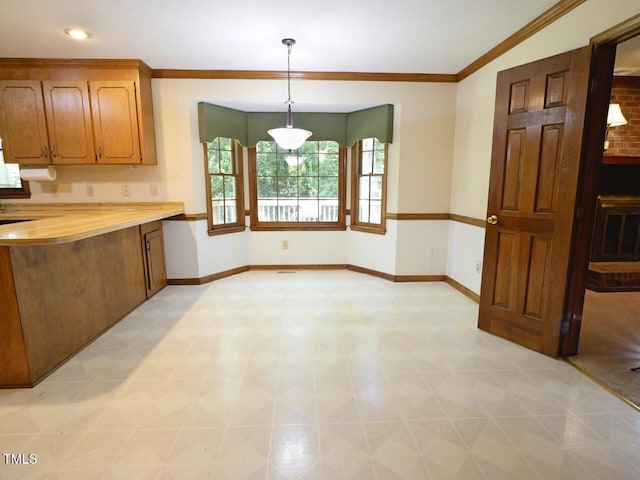 637 Shadywood Ln, Raleigh, NC 27603 - kitchen with light floors, ornamental molding, brown cabinetry, and hanging light fixtures