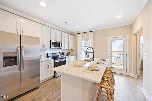 549 Forestville Rd, Wake Forest, NC 27587 - kitchen featuring appliances with stainless steel finishes, light wood-type flooring, a breakfast bar area, an island with sink, and ornamental molding