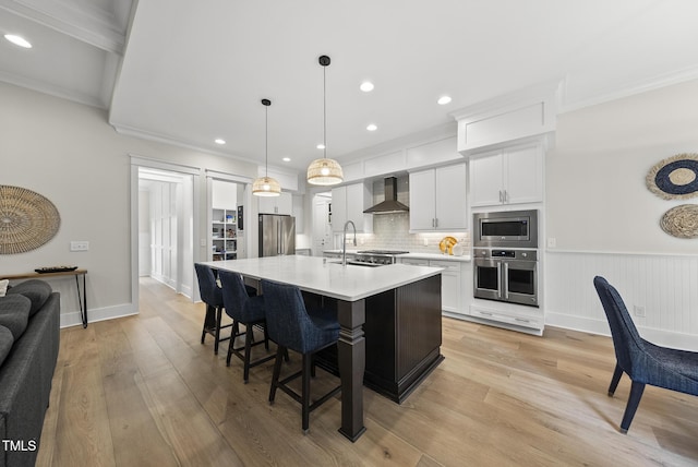1325 Mackinaw Dr, Wake Forest, NC 27587 - kitchen with stainless steel appliances, wall chimney range hood, ornamental molding, light countertops, and a center island with sink