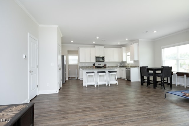 200 Sweet Violet Dr, Youngsville, NC 27596 - kitchen with stainless steel appliances, ornamental molding, a kitchen breakfast bar, white cabinetry, and a center island