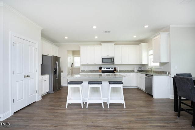 200 Sweet Violet Dr, Youngsville, NC 27596 - kitchen with appliances with stainless steel finishes, crown molding, white cabinetry, a kitchen island, and dark wood-style floors