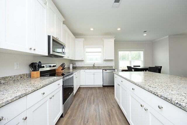 200 Sweet Violet Dr, Youngsville, NC 27596 - kitchen with appliances with stainless steel finishes, ornamental molding, wood finished floors, white cabinetry, and light stone counters
