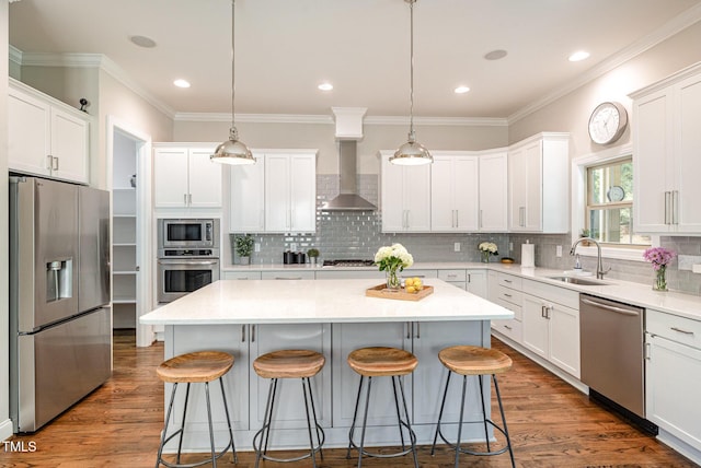 1020 Regency Cottage Pl, Cary, NC 27518 - kitchen featuring appliances with stainless steel finishes, wall chimney range hood, a center island, a breakfast bar, and crown molding