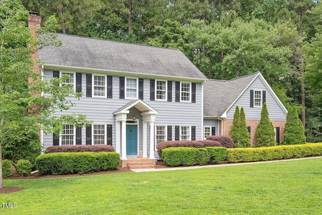 2008 Corberrie Ln, Raleigh, NC 27613 - colonial inspired home featuring a front lawn, a chimney, roof with shingles, and brick siding