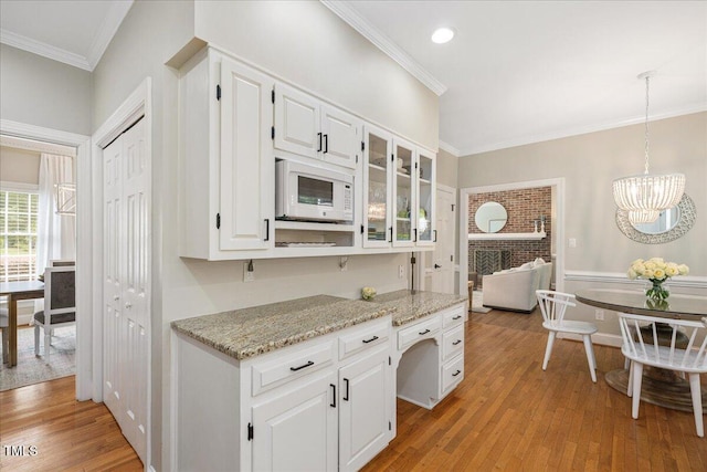 2008 Corberrie Ln, Raleigh, NC 27613 - kitchen with white microwave, white cabinets, light wood-style flooring, ornamental molding, and glass insert cabinets