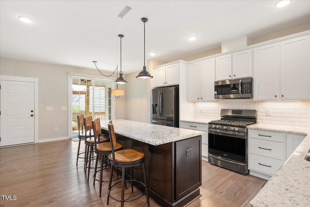 513 Brooks St, Wake Forest, NC 27587 - kitchen with stainless steel appliances, tasteful backsplash, white cabinetry, a kitchen island, and wood finished floors