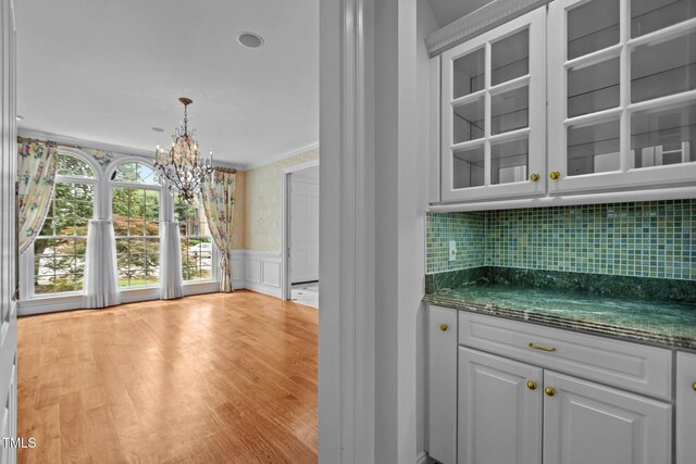 4315 Sugar Pine Ln, Durham, NC 27705 - bar area with a chandelier, wainscoting, crown molding, light wood-style floors, and tasteful backsplash