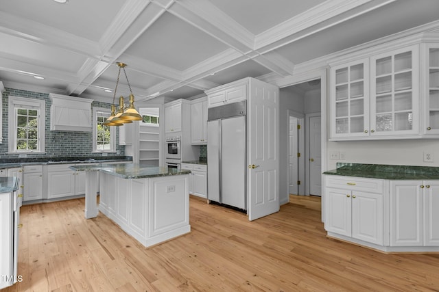 4315 Sugar Pine Ln, Durham, NC 27705 - kitchen with built in refrigerator, premium range hood, white cabinetry, light wood-style flooring, and backsplash