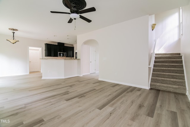 616 Cheselden Dr, Durham, NC 27713 - unfurnished living room with ceiling fan, arched walkways, light wood-style flooring, and stairs