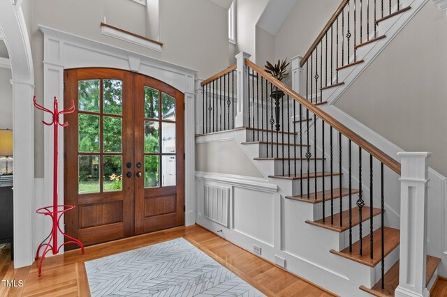 763 Heritage Arbor Dr, Wake Forest, NC 27587 - entrance foyer featuring french doors, wood finished floors, a decorative wall, stairway, and wainscoting
