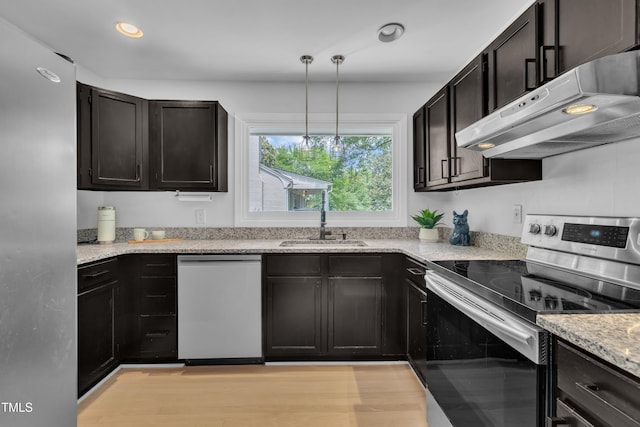 3205 Dell Dr, Raleigh, NC 27609 - kitchen with stainless steel appliances, under cabinet range hood, light stone counters, decorative light fixtures, and dark cabinets