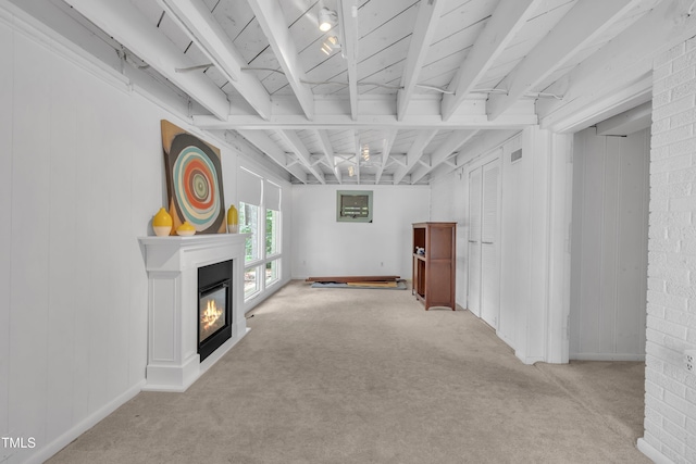 3205 Dell Dr, Raleigh, NC 27609 - unfurnished living room with carpet flooring, a glass covered fireplace, and beamed ceiling