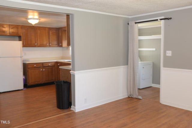 521 S Lombard St, Clayton, NC 27520 - kitchen with freestanding refrigerator, washer / dryer, brown cabinets, light countertops, and wood finished floors