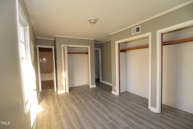 521 S Lombard St, Clayton, NC 27520 - unfurnished bedroom featuring two closets, wood finished floors, and ornamental molding