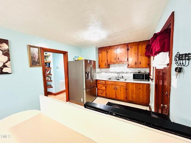 1337 Maple St, Rocky Mount, NC 27803 - kitchen with stainless steel appliances, brown cabinets, light countertops, backsplash, and a textured ceiling