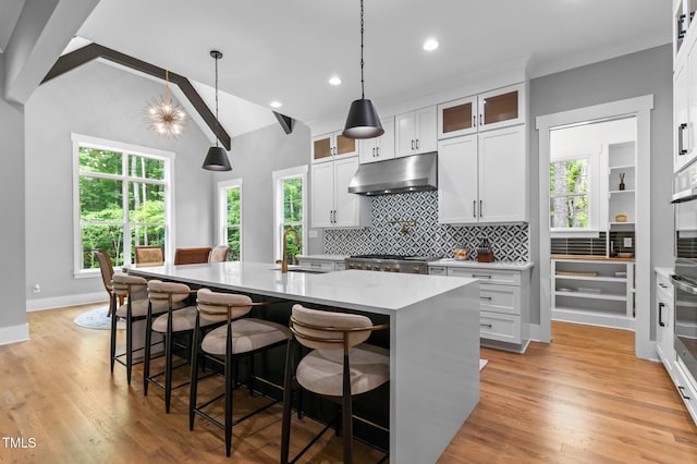 310 Hidden Lake Dr, Youngsville, NC 27596 - kitchen with under cabinet range hood, a center island with sink, tasteful backsplash, recessed lighting, and light countertops
