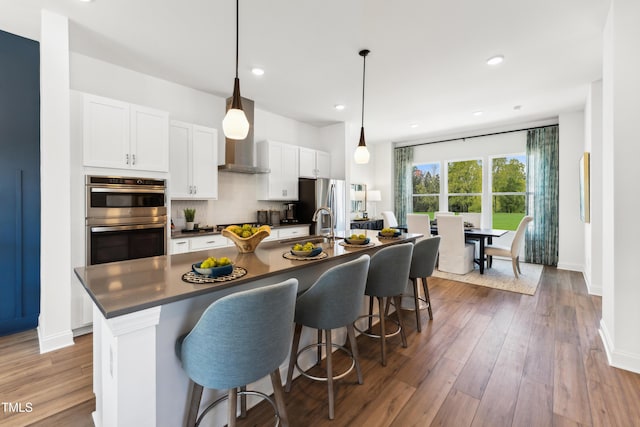 2808 Kempthorne Rd Lot 61, Cary, NC 27519 - kitchen featuring stainless steel appliances, dark countertops, an island with sink, white cabinetry, and a kitchen breakfast bar