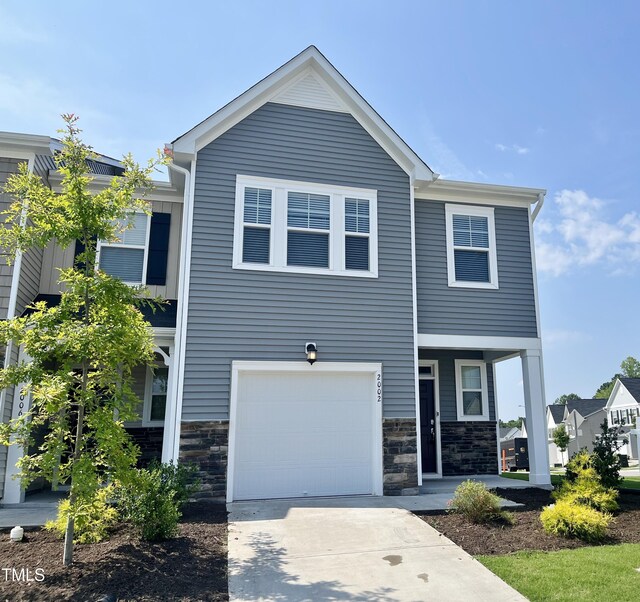 2002 Strickland Oak Way, Durham, NC 27703 - view of front facade with an attached garage, stone siding, concrete driveway, and covered porch