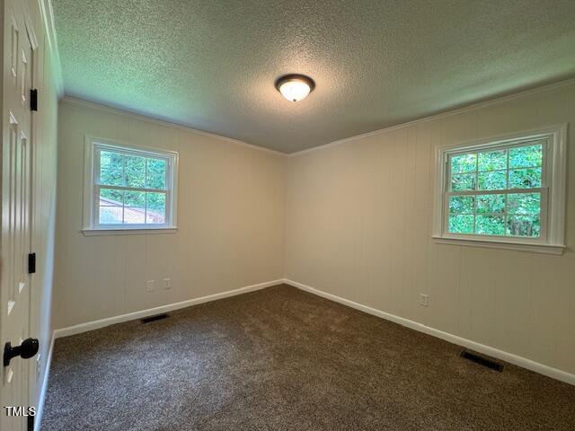 818 Wakefield Ave, Henderson, NC 27536 - unfurnished room with dark colored carpet, ornamental molding, and a textured ceiling