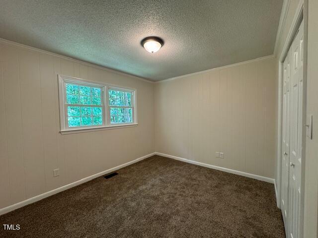 818 Wakefield Ave, Henderson, NC 27536 - spare room with a textured ceiling, dark carpet, and crown molding