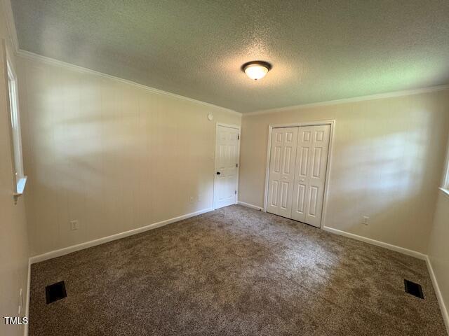 818 Wakefield Ave, Henderson, NC 27536 - unfurnished bedroom featuring ornamental molding, carpet floors, a textured ceiling, and a closet