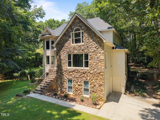 6001 Waters Way Dr, Raleigh, NC 27606 - view of front of house with stone siding, a front yard, stairs, roof with shingles, and concrete driveway