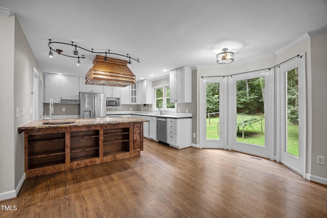 6001 Waters Way Dr, Raleigh, NC 27606 - kitchen with appliances with stainless steel finishes, wood finished floors, white cabinets, glass insert cabinets, and ornamental molding