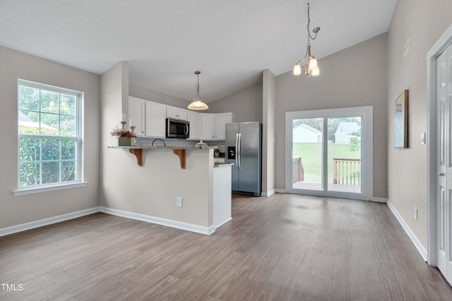 5000 Silverdene St, Raleigh, NC 27616 - kitchen with appliances with stainless steel finishes, a peninsula, light wood finished floors, white cabinetry, and a breakfast bar area