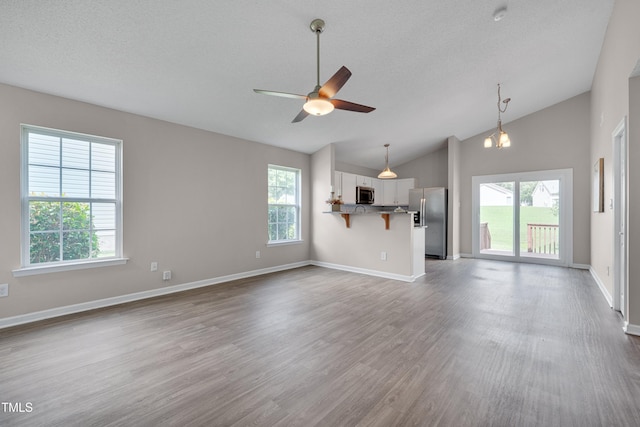 5000 Silverdene St, Raleigh, NC 27616 - unfurnished living room featuring plenty of natural light, lofted ceiling, wood finished floors, a ceiling fan, and a textured ceiling