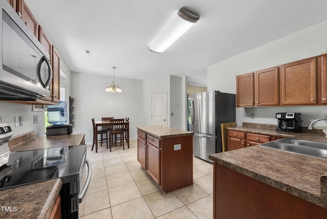702 Pitch Pine Dr, Creedmoor, NC 27522 - kitchen featuring stainless steel appliances, dark countertops, a kitchen island, a chandelier, and brown cabinetry
