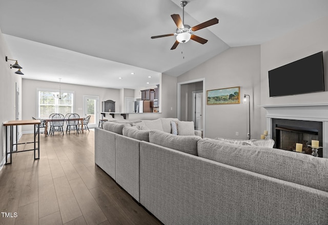 244 Lasswade Ct, Zebulon, NC 27597 - living area with a ceiling fan, dark wood-style floors, a fireplace, vaulted ceiling, and a chandelier