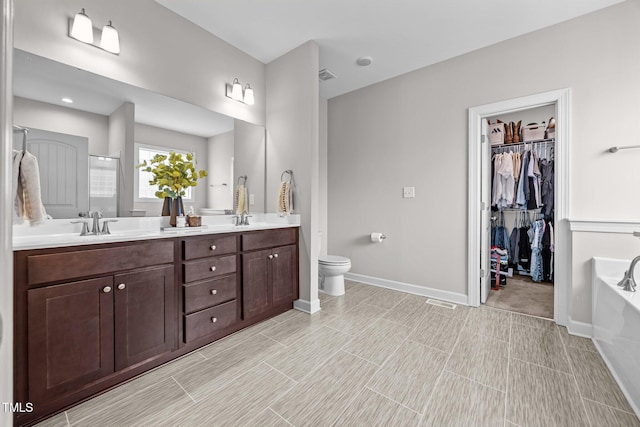 244 Lasswade Ct, Zebulon, NC 27597 - bathroom featuring double vanity, a bath, a shower stall, and a spacious closet