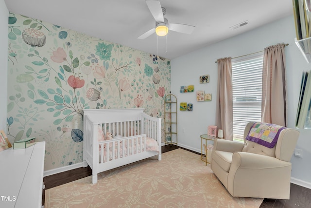 2626 Nassau Trce, Fuquay Varina, NC 27526 - bedroom featuring a crib, wood finished floors, wallpapered walls, and ceiling fan