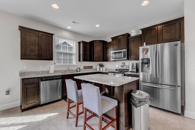 525 Willow Breeze Ct, Zebulon, NC 27597 - kitchen featuring stainless steel appliances, dark brown cabinetry, a kitchen breakfast bar, a kitchen island, and recessed lighting